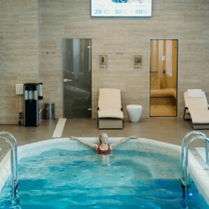 Woman enjoying leisure time in an indoor swimming pool, surrounded by modern amenities.